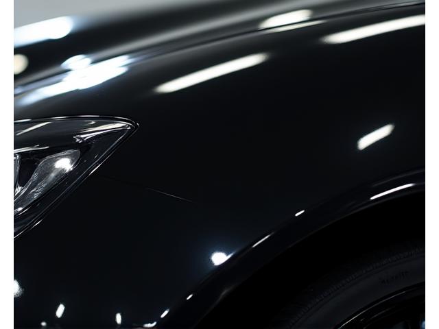 Surface de carrosserie noire reflétant parfaitement la lumière après une correction de peinture